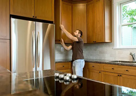 A man in brown shirt standing next to kitchen counter.