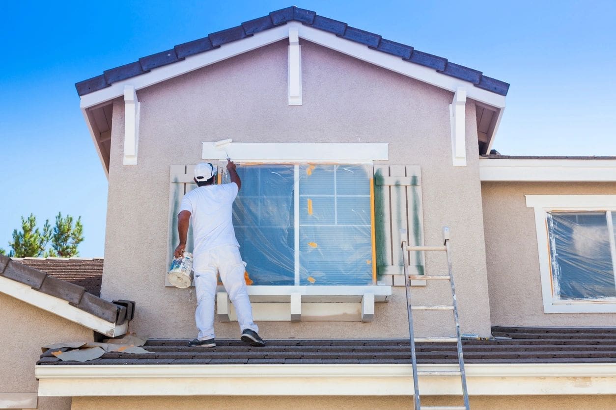 A man painting the outside of a house.