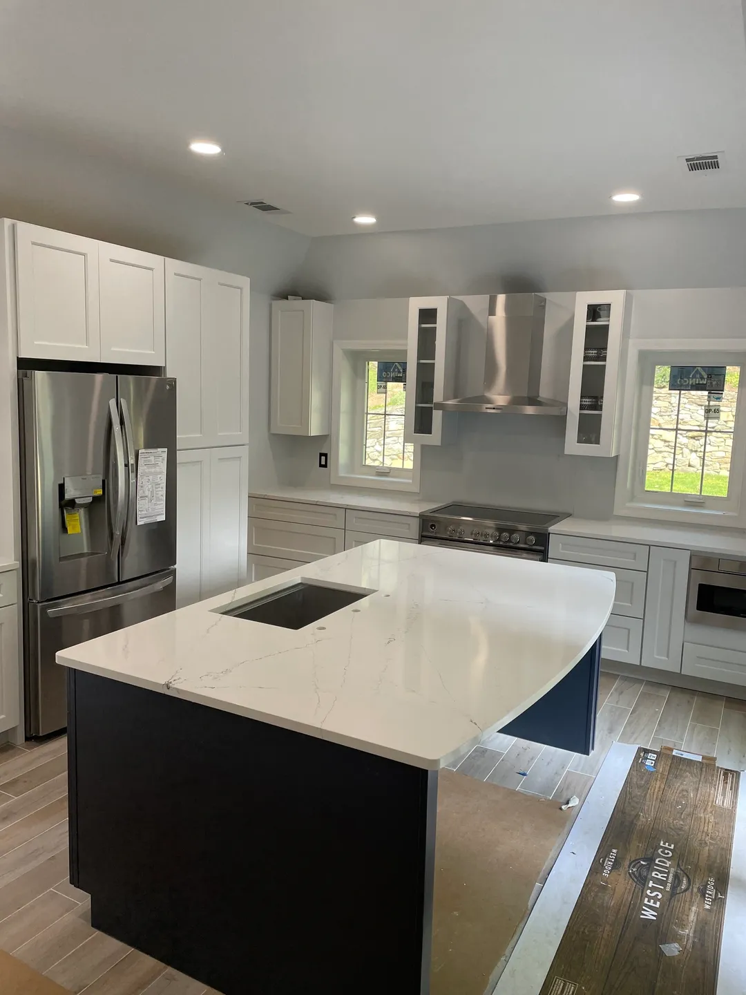 A kitchen with white cabinets and black island.