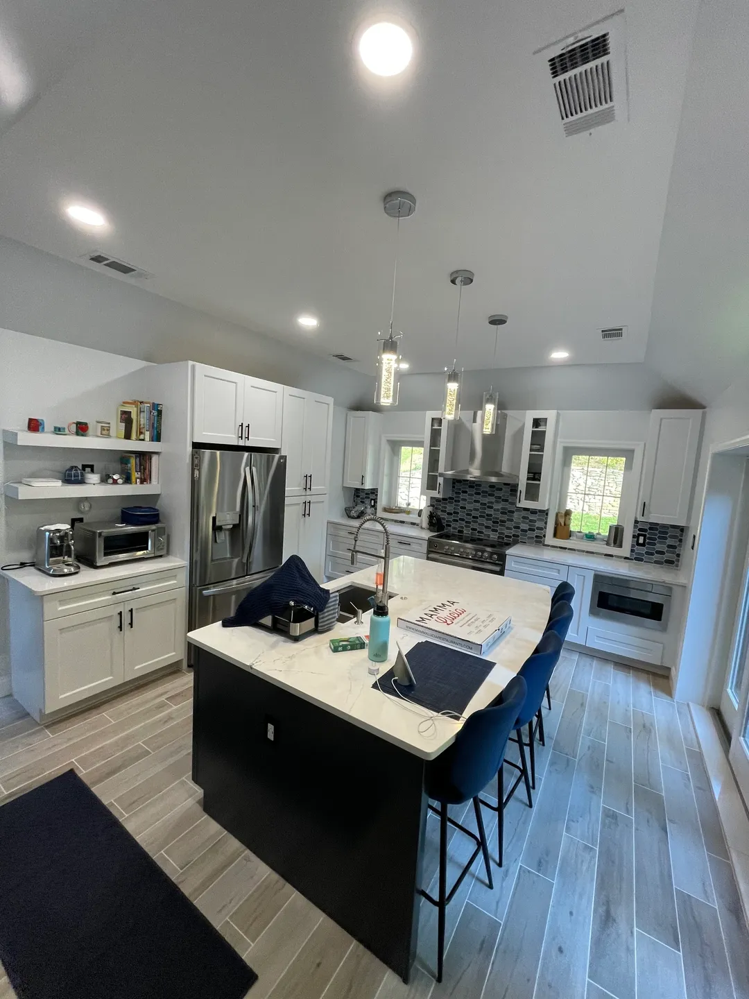 A kitchen with white cabinets and blue chairs.