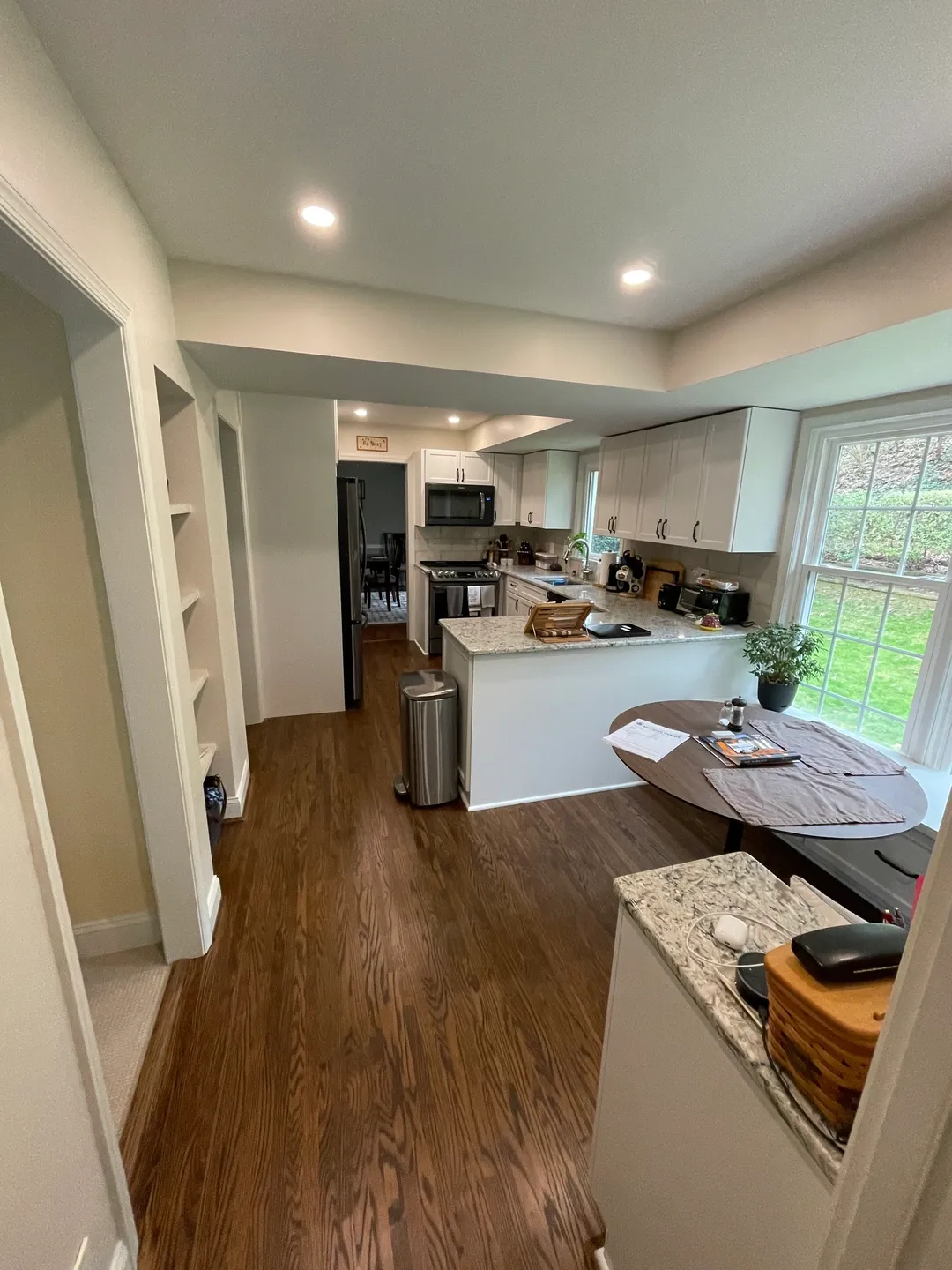 A kitchen with white cabinets and wood floors.