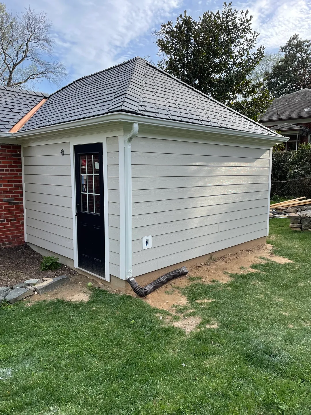 A white shed with black door and windows.