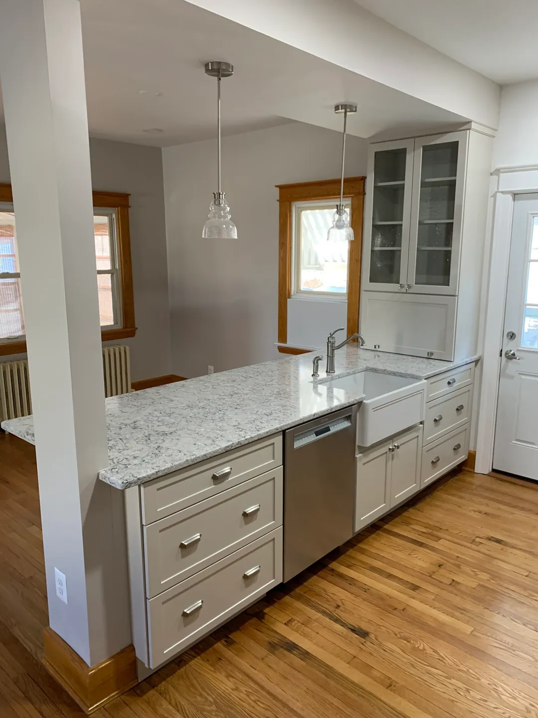 A kitchen with white cabinets and wooden floors.