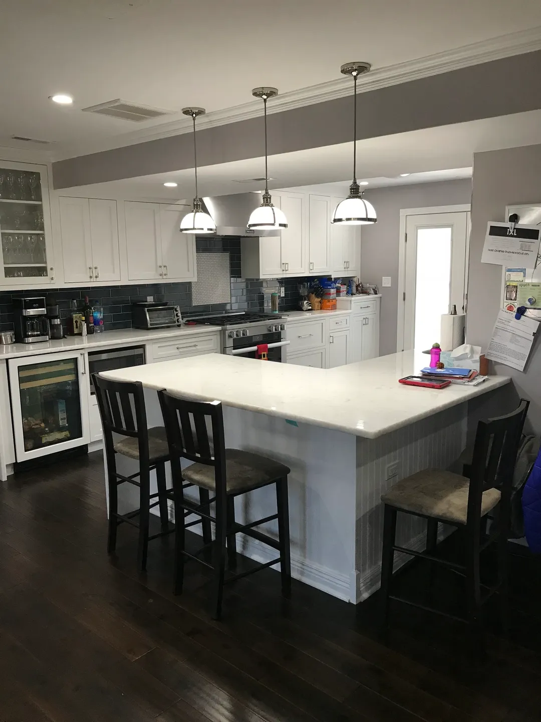 A kitchen with white cabinets and black chairs.