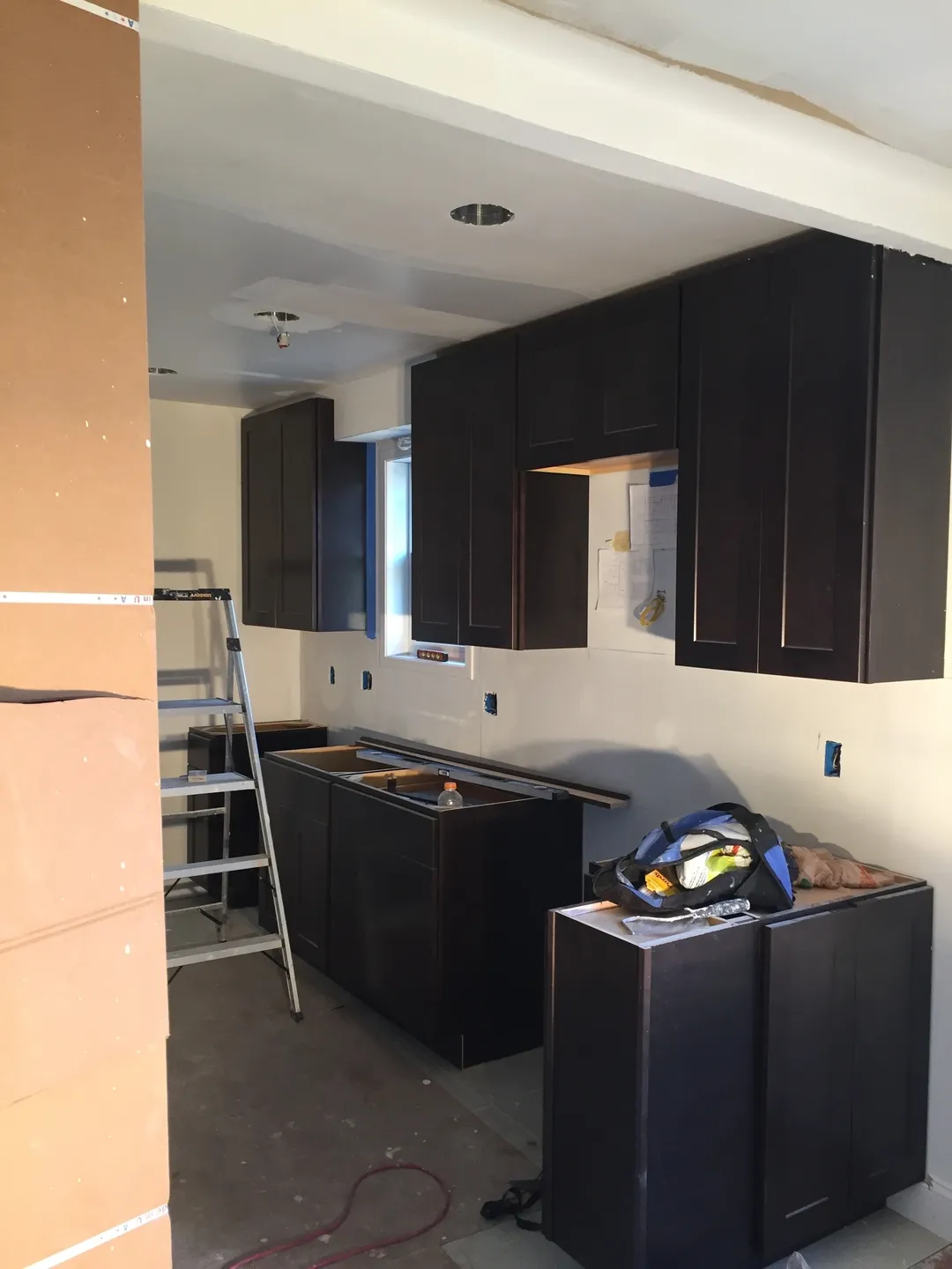 A kitchen with dark cabinets and a ladder