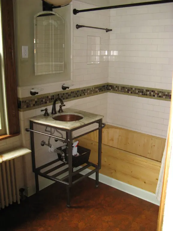 A bathroom with wood floors and tile walls.